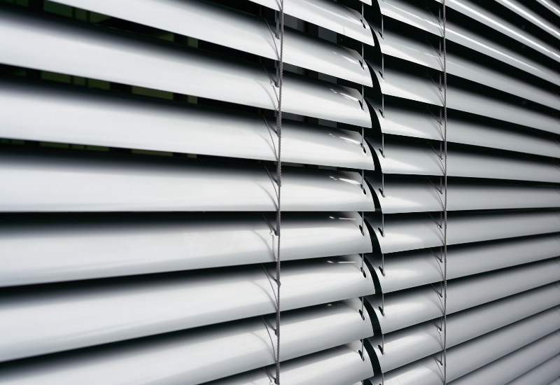 Silver aluminum blinds partially open on window in Tucson, AZ